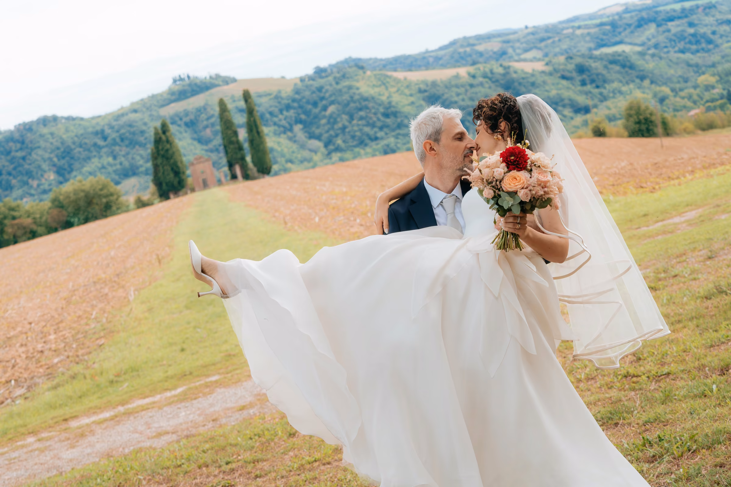 Luana e Giacomo — Lo sposo solleva la sposa nel paesaggio